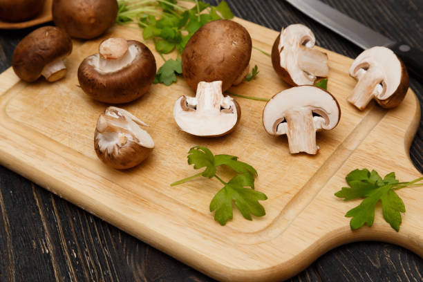 istock Cutted royal raw champignons with green on wooden board. 656814370