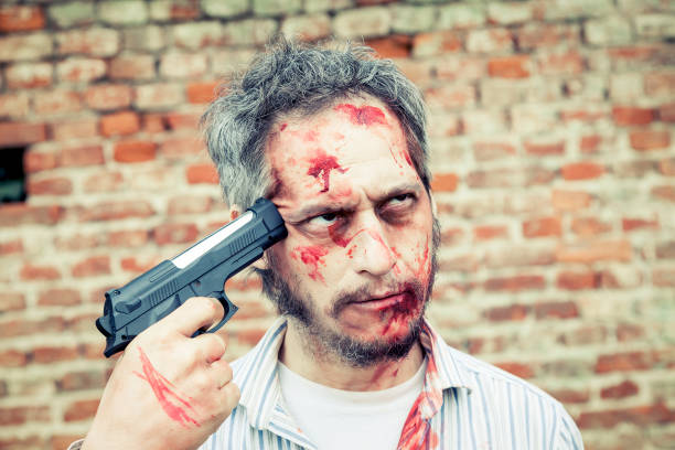 istock scary zombie tries to shoot himself in the head 656822286