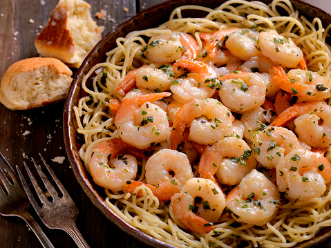 Pasta spaghetti with shrimps, mussels, clams on wooden table. Italian typical spaghetti recipe with seafood and tomatoes.