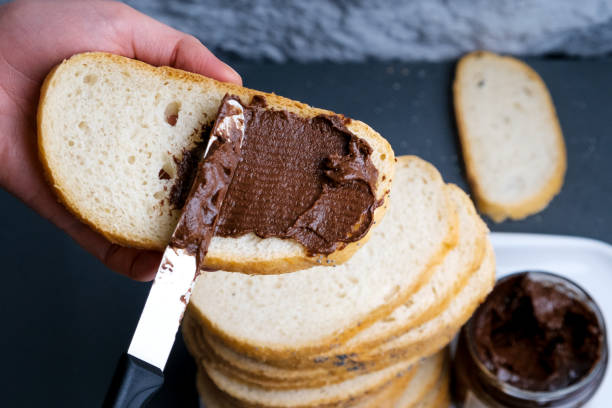 Sweet chocolate cream in jar on table. Nutella with buttered bread.