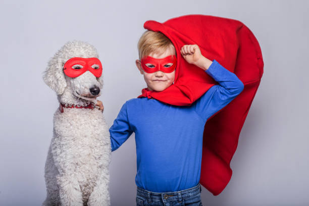 handsome little superman with dog. superhero. halloween. studio portrait over white background - real people blue white friendship imagens e fotografias de stock