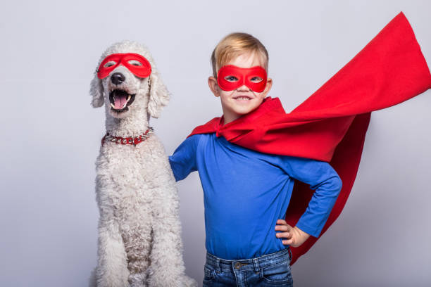 handsome little superman with dog. superhero. halloween. studio portrait over white background - real people blue white friendship imagens e fotografias de stock