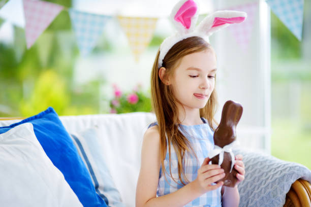 istock Cute little girl wearing bunny ears eating chocolate Easter rabbit 656849360