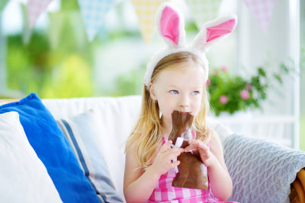 istock Cute little girl wearing bunny ears eating chocolate Easter rabbit 656849412