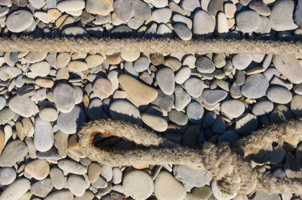 old worn battered marine rope on the pebble beach on a Sunny summer day, top view