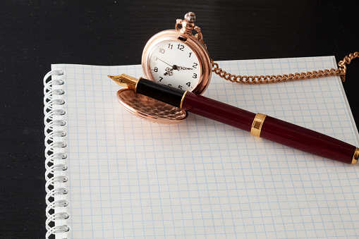 Beautiful pen and pocket watch on notebook