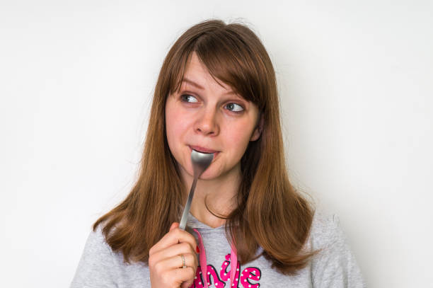 istock Young beautiful woman with spoon in mouth 656915922