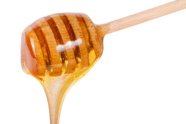 istock Honey flowing from wooden stick isolated on white background 656922820