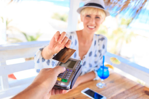 istock Young woman using credit card for contactless payment on beach 656936784