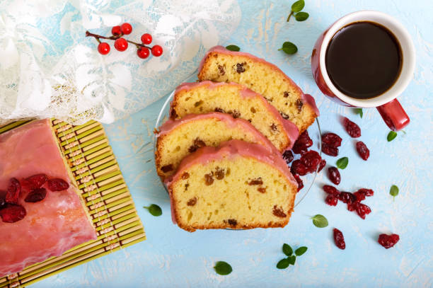 istock Soft festive fruitcake with raisins and dried cranberries, decorated with sugar icing cut by pieces and cup of coffee on a light background. Top view. 656937200