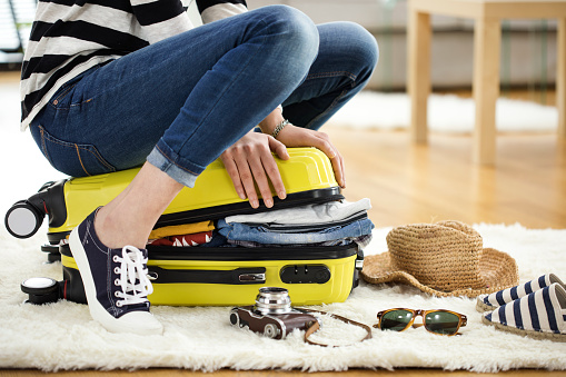 Young woman packing suitcase in preparation for going travel