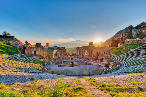 Ancient theatre of Taormina with Etna erupting volcano at sunset