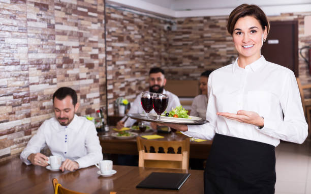 istock Young woman waiter bringing order for visitors 656943426