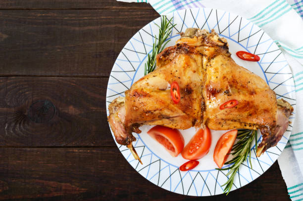 istock Baked rabbit legs on a plate on a dark wooden background. Dietary menu. Top view. 656950988