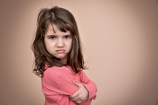 Angry and pouting cute young girl with crossed arms