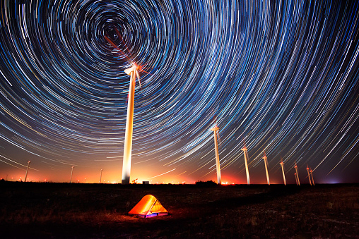 Long time exposure night landscape with star trails over a wind farm