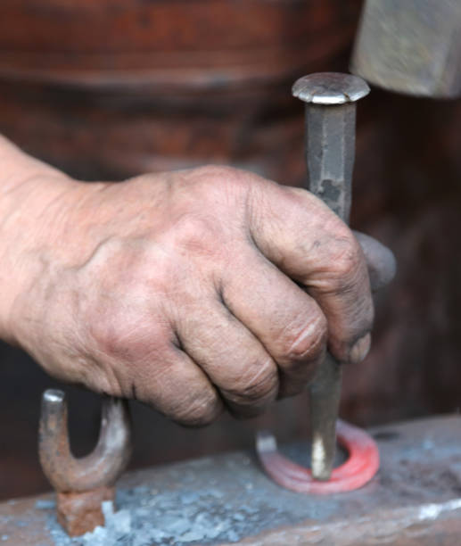 istock hand elder blacksmith who uses an iron awl over a anvil 656979898