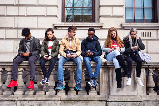 Group of young teenagers students using smartphone on a school break