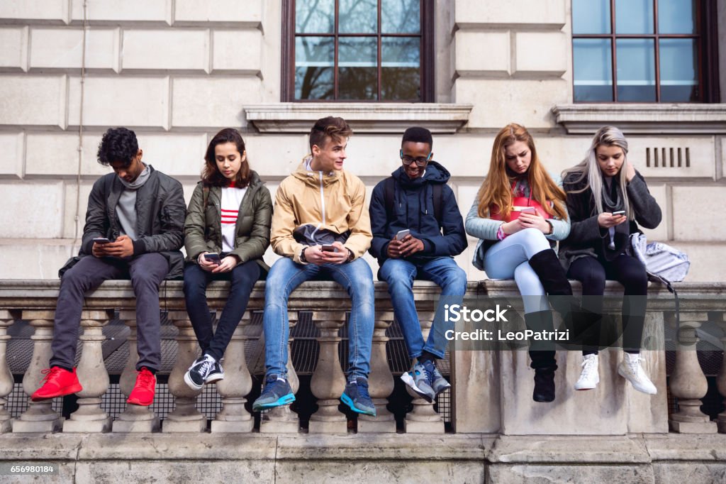 Teenagers students using smartphone on a school break Group of young teenagers students using smartphone on a school break Teenager Stock Photo