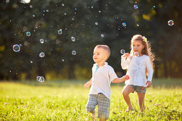 istock Young boy and girl looking at soap bubbles 656993548