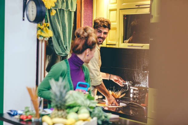 coppia sorridente che cucina insieme - italian culture women looking at camera cheerful foto e immagini stock