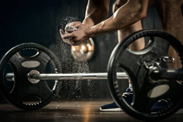 background sportivo. giovane atleta che si prepara per l'allenamento di sollevamento pesi. mano powerlifter in talco che si prepara alla pressa da banco - crouching barbell weightlifting weight training foto e immagini stock