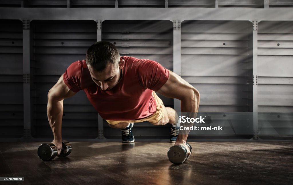 Sport. Handsome man doing push ups exercise with one hand in fitness gym Sport and Fitness Men Stock Photo
