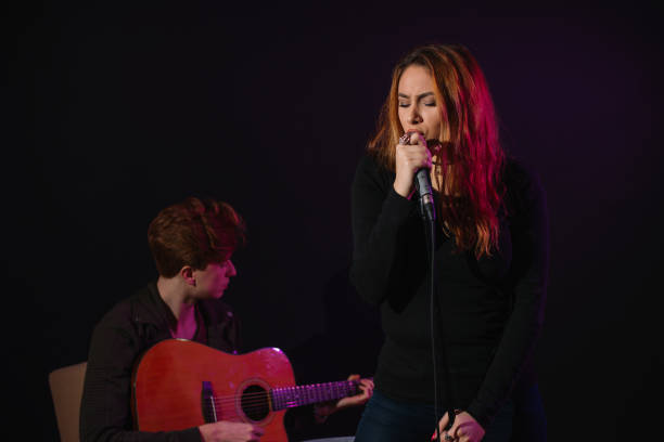 istock Beautiful girl singing in the studio while young man plays guitar 657045292