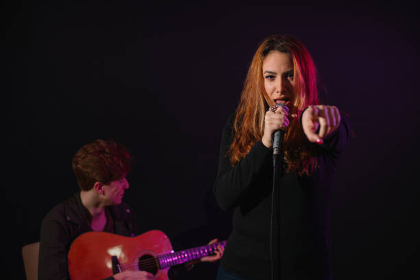 istock Beautiful girl singing in the studio while young man plays guitar 657045294