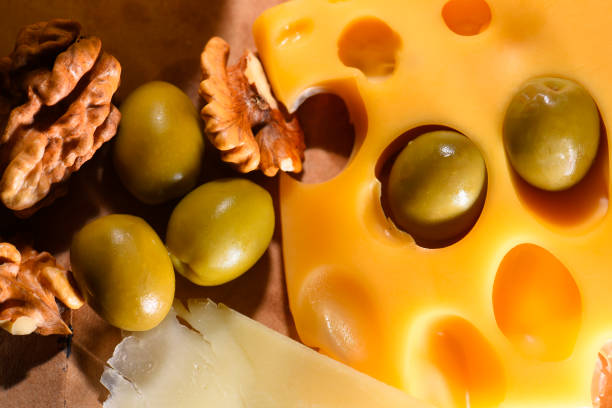 A fork holds a piece of fresh cheese above a colorful platter of vegetables.