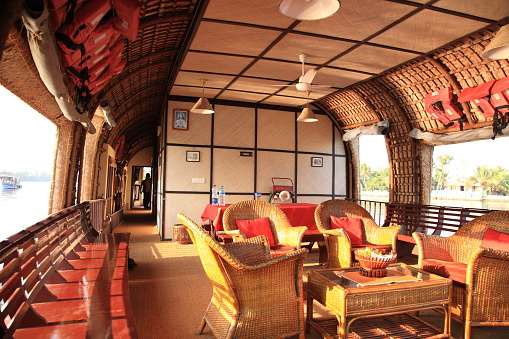 Alleppey Backwaters, Kerala, India - January 24, 2017: A houseboat is comfortably furnished with an open lounge sailing on the Kerala backwaters. The Kerala houseboats in the backwaters are one of the prominent tourist attractions in Kerala. The Kerala Backwaters are a network of interconnected canals, rivers, lakes and inlets.