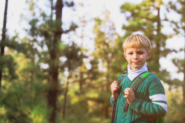istock happy little boy with backpack travel in green forest 657073348