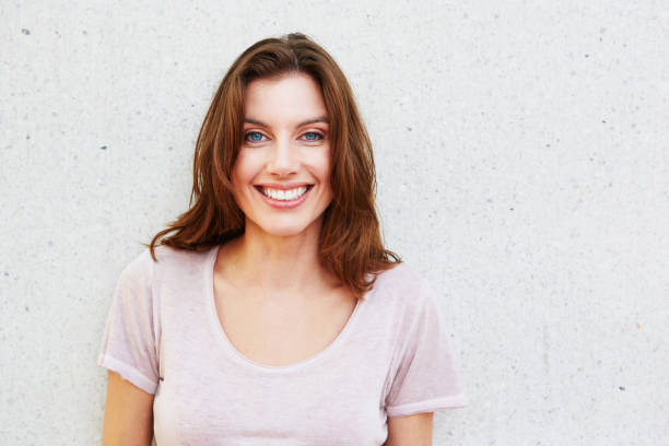 istock beautiful young woman smiling against white wall 657079784