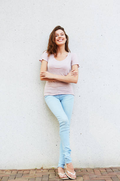 istock happy and beautiful young woman leaning against wall 657079850