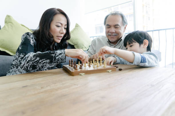 istock Young boy playing chess with grandparents 657083944