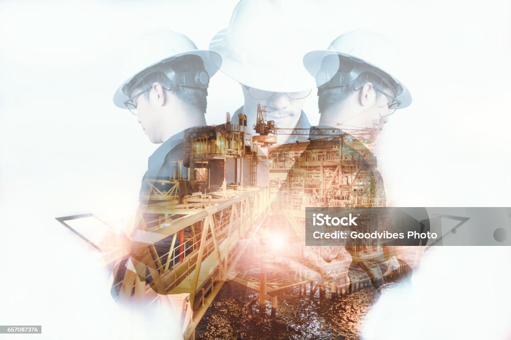 Double exposure of Engineer or Technician man with safety helmet operated platform or plant by using tablet with offshore oil and gas platform background for oil and gas business concept Engineer Stock Photo