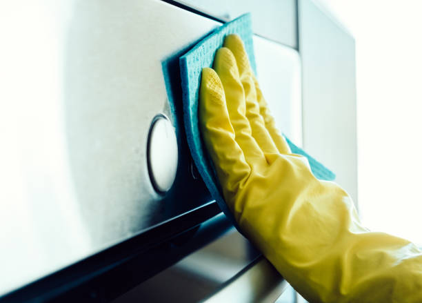 istock Man's hand in yellow glove cleaning the kitchen oven with rag 657102866