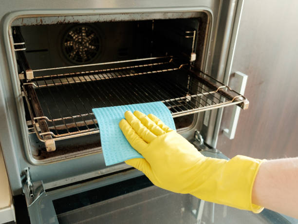 istock Man with rag and rubber gloves cleaning kitchen stove 657102886