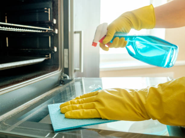istock Man's hand in yellow rubber glove with rag cleaning kitchen oven 657102906