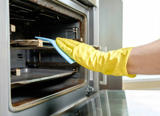 istock Man with rag and rubber gloves cleaning kitchen stove 657102912