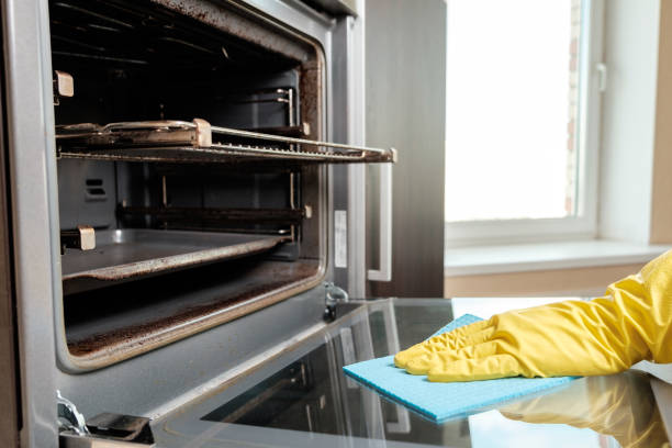 istock Man with rag and rubber gloves cleaning kitchen stove 657102930