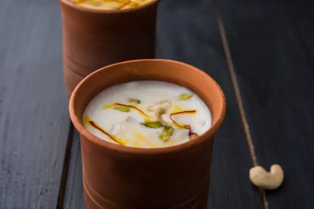 Authentic Indian cold drink made up of curd, milk & malai called Lassi in saffron / kesar flavour, also called kesariya or keshariya or kesar lassi, served in traditional indian terracotta glasses