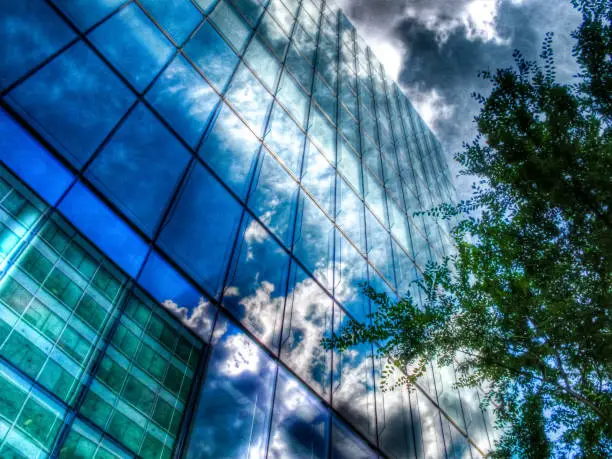 Dramatic sky reflected in the glass walls of a downtown office building.