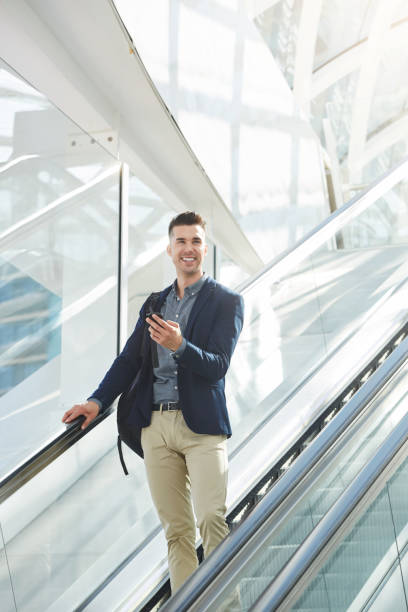 istock handsome business man on escalator smiling with smart phone 657110326