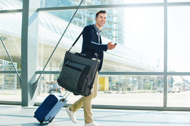 istock man walking with luggage and phone in station smiling 657110518