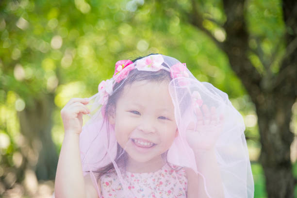 Little asian cute girl in pink dress smiling in park