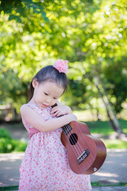 istock girl holding ukulele in park 657110832
