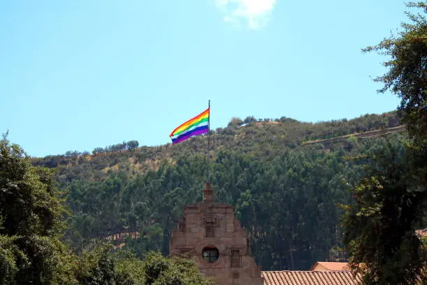 rainbow flag hoisted on an antique old building over the skyline in the metropolis city cuzco in the andes, the start of every tour in the sacred valley discovering the high culture of the inca peru