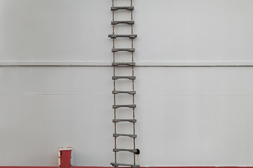 rope ladder hanging on white wall hull on ship