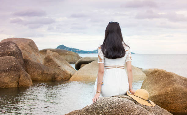istock Girl sitting on the seaside rocks 657145880